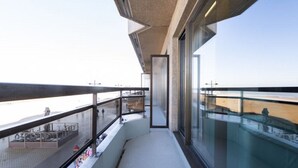 A modern balcony with glass railings overlooking a waterfront area.