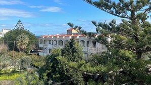 A building with a red-tiled roof and arched windows, surrounded by greenery. - Mark Hotel (Heraklion)