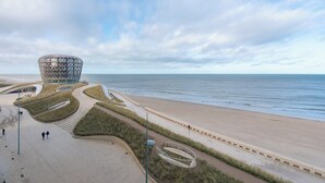 A coastal promenade with a distinctive modern building, a sandy beach, and a clear sky. - Family spot by the coastal trails (MIDDELKERKE)
