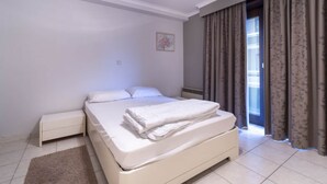 A bedroom with a bed, a nightstand, a window with curtains, and a small wall decoration. - Apartment in Middelkerke near Beach & Casino (MIDDELKERKE)