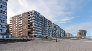 Un hotel moderno de varios pisos, una playa en primer plano y un edificio esférico distintivo al fondo.