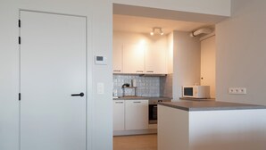 Une cuisine moderne avec des armoires blanches, un four à micro-ondes encastré et un plan de travail en bois.