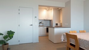 Une cuisine moderne avec des meubles blancs, un îlot central et un coin repas comprenant une table et des chaises.
