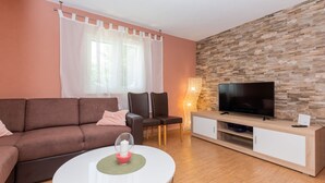 A living room with a sofa, chairs, a TV, and a stone wall. - Villa Anatea by Villas Guide (Cista Provo)