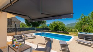 A poolside area with a covered seating area, lounge chairs, and a hot tub. - Villa Anatea by Villas Guide (Cista Provo)