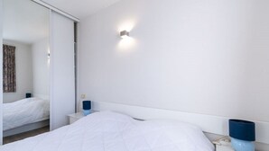 Ein modernes Hotelzimmer mit einem großen Bett, einem Nachttisch mit Lampe und einer Wandleuchte.