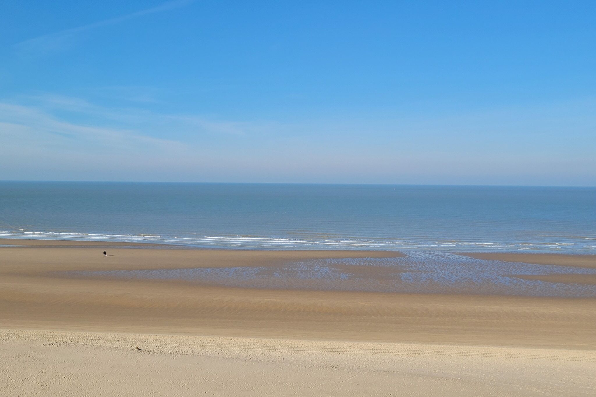A wide beach with a clear sky and calm sea.