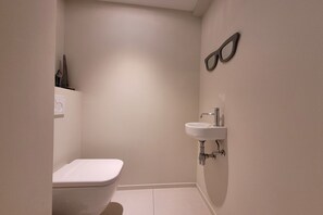 A small, modern bathroom with a toilet, a sink, and a mirror. - Apartment in Nieuwpoort with Stunning Sea Views (MIDDELKERKE)