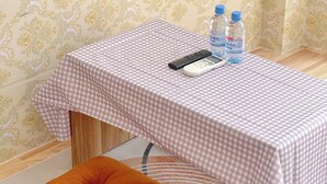 A room with a checkered tablecloth, two water bottles, a remote control, and a tufted orange ottoman. - Corgi House Homestay Nha Trang 2 (Nha Trang)