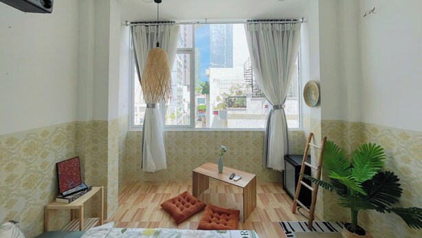 A room with a bed, a small table with a vase, a projector, and a window with curtains. - Corgi House Homestay Nha Trang 2 (Nha Trang)