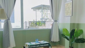 A hotel room with a bed, a table with a motivational poster, a potted plant, and a view of the outside balcony. - Corgi House Homestay Nha Trang 2 (Nha Trang)