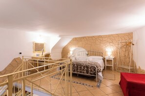 A bedroom with a bed, a nightstand, a mirror, a red table, and a staircase. - Fiera House in the City Center (Catania)