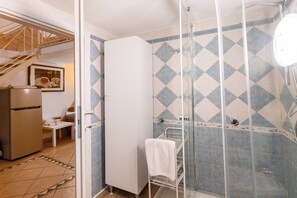 A bathroom with a shower, a white cabinet, and a tiled wall. - Fiera House in the City Center (Catania)