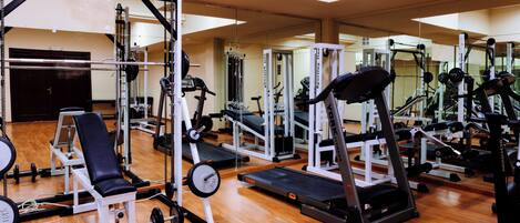 A gym with various exercise equipment, including treadmills, weight machines, and free weights.