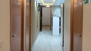 Un pasillo con puertas de madera, piso de baldosas e iluminación empotrada.