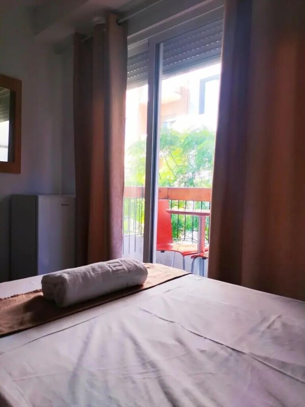 Relax in a spacious room with a large bed and a balcony offering a view of the outdoors.