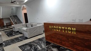 Ein Empfangsbereich mit einem Holzbüro, grauen Sofas und einem Boden mit Marmoroptik.