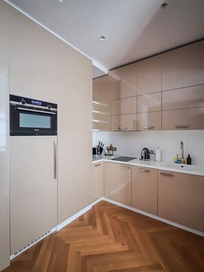 Una cocina moderna con horno empotrado, lavamanos y piso de madera.