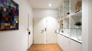 A hallway with a herringbone floor, white walls, and a colorful abstract painting.