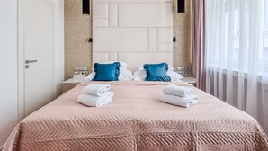 A hotel room with a large bed, two pillows, a bedside table, and a window with curtains.