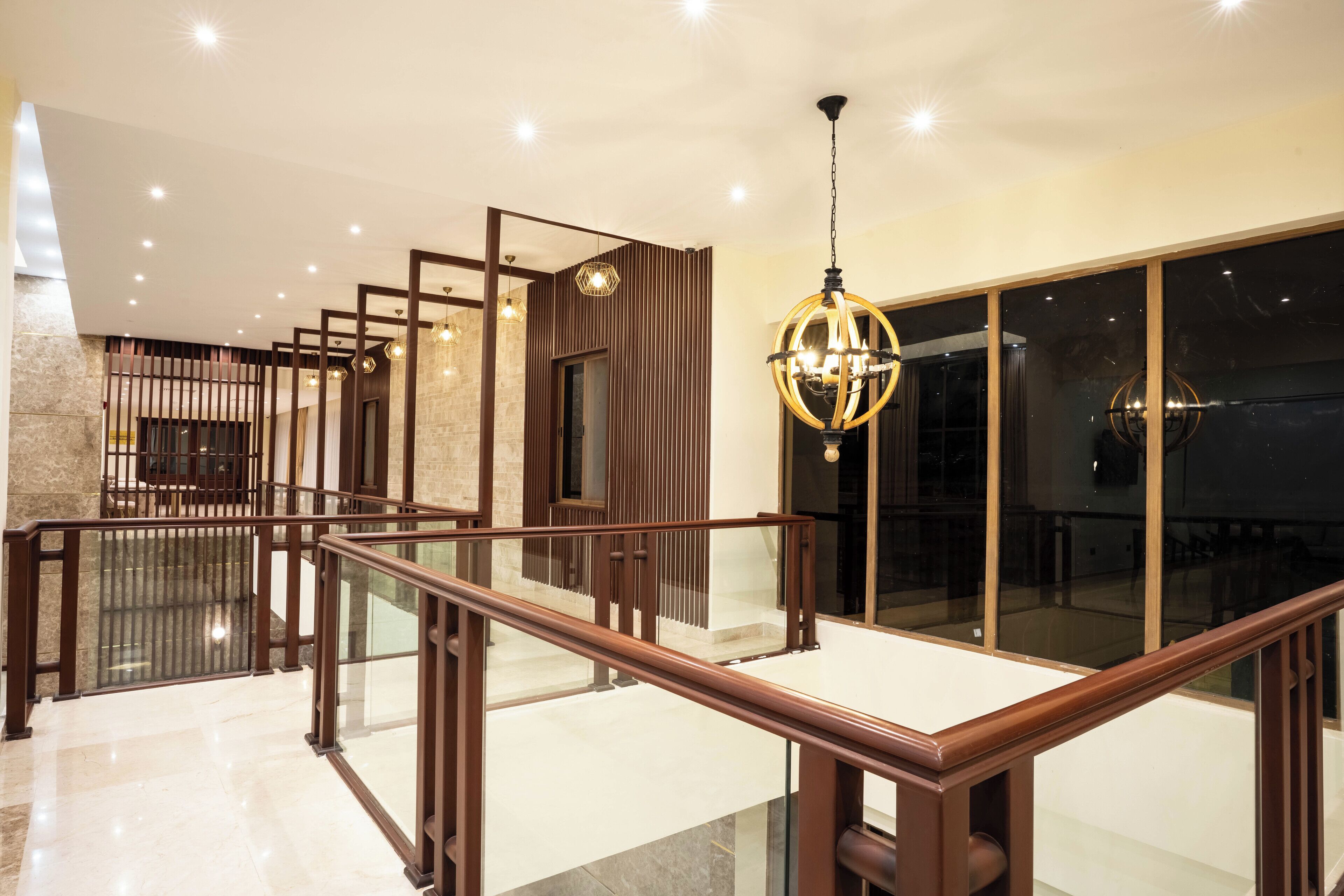 A modern interior with a glass railing, wooden paneling, and a chandelier.