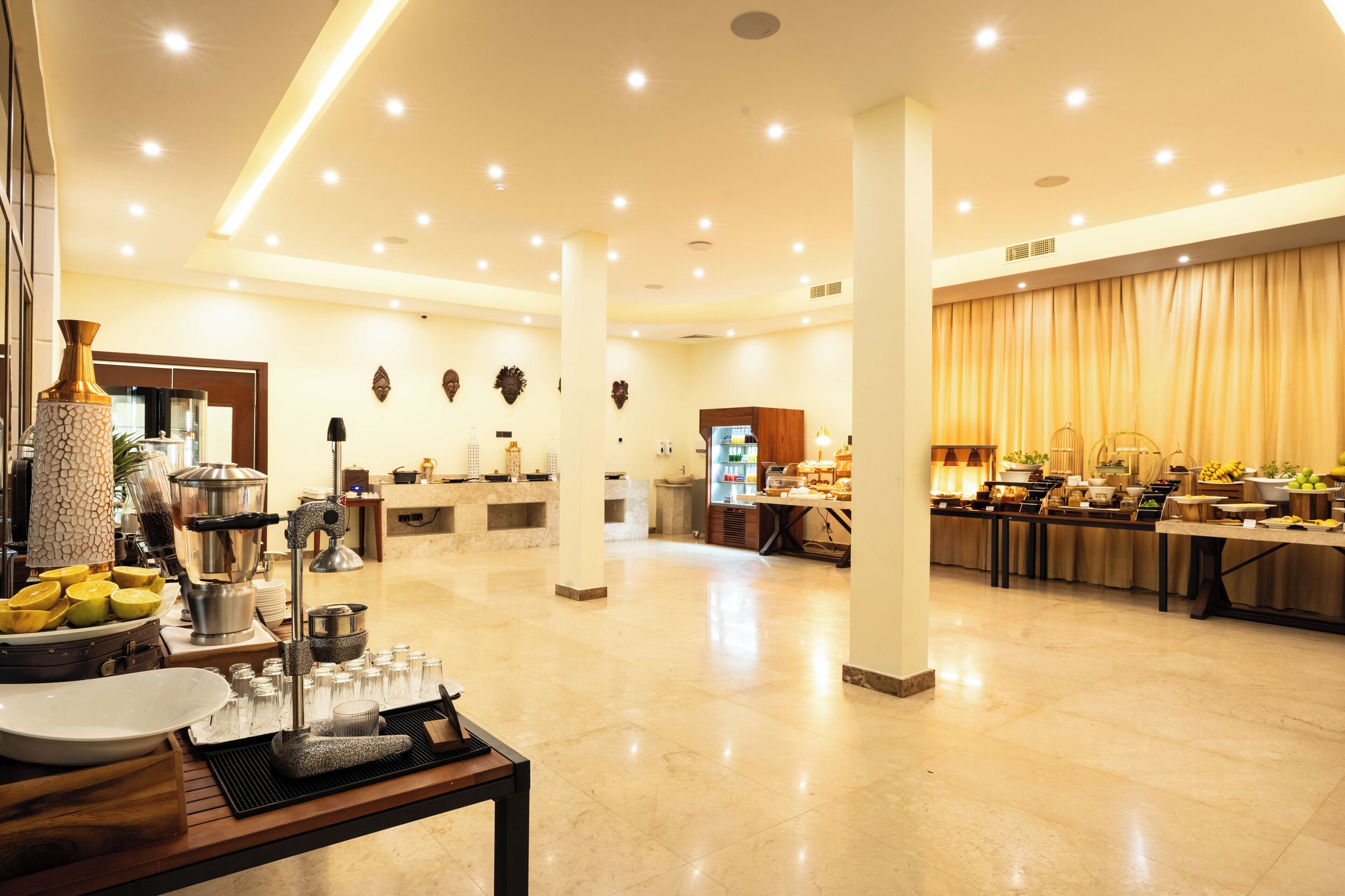 A spacious hotel lobby with a buffet area, a reception desk, and a large window with curtains.