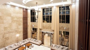 A spacious lobby with a high ceiling, large windows, and a seating area with sofas and a coffee table. - Treetop by Eight Continents, Zanzibar (Unguja Ukuu)