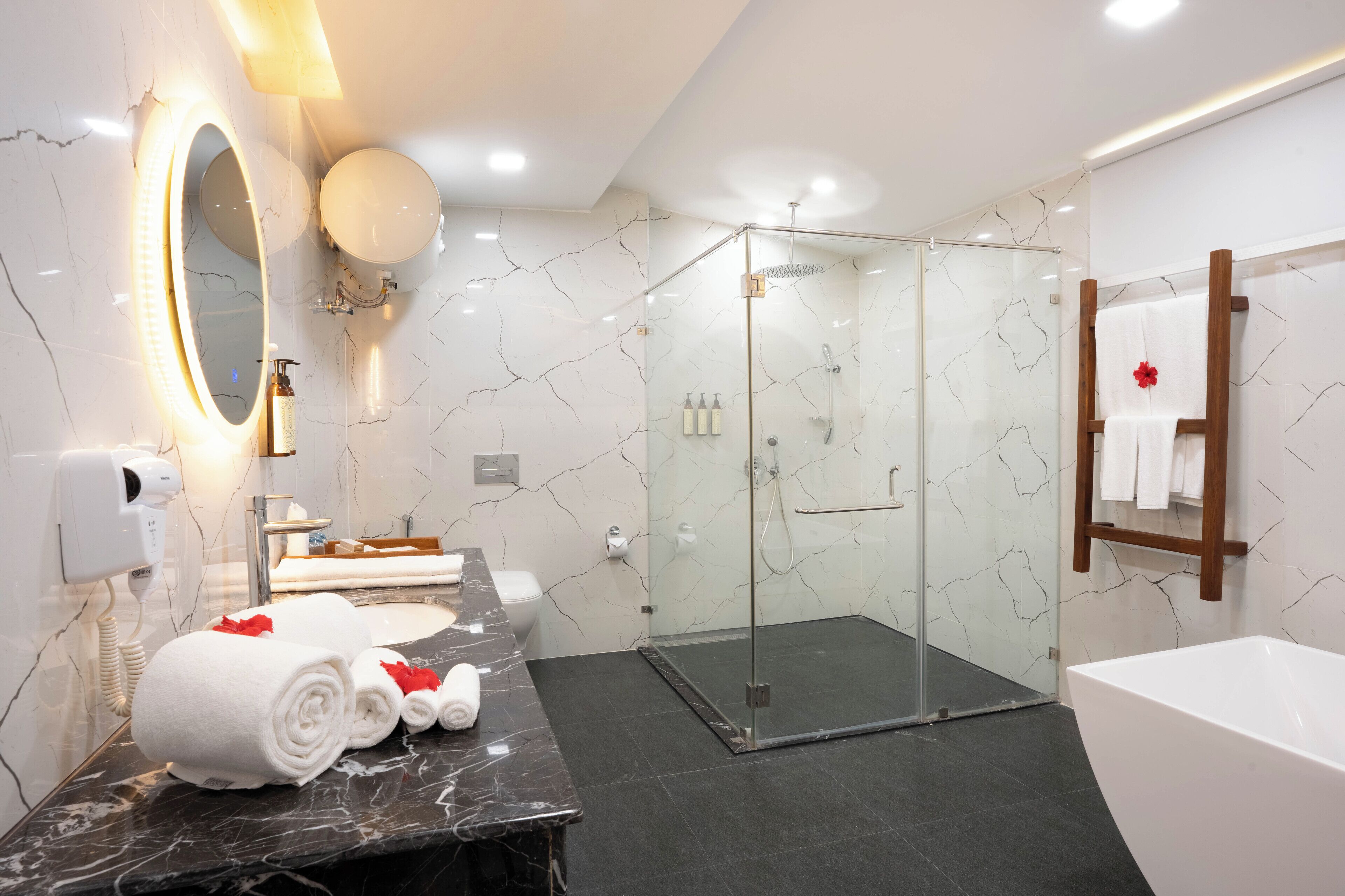 A modern bathroom with a glass-enclosed shower, a marble vanity, and a large mirror.