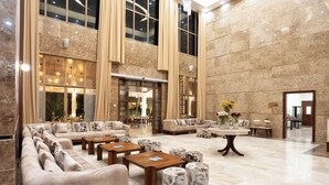 A spacious lobby with high ceilings, large windows, and a mix of seating areas including sofas and tables. - Treetop by Eight Continents, Zanzibar (Unguja Ukuu)
