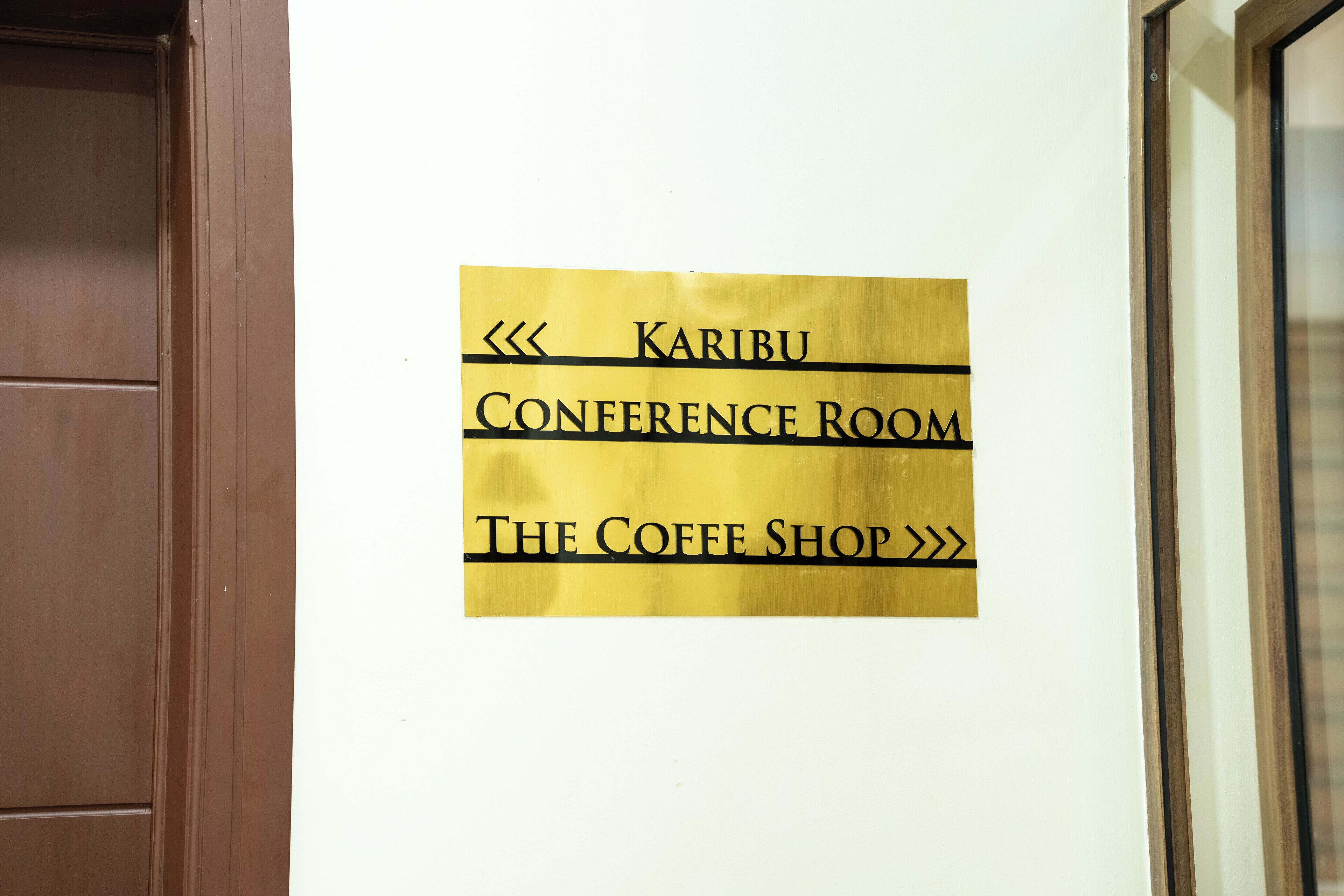 Señal que indica la ubicación de la Sala de Conferencias Karibu y The Coffee Shop.
