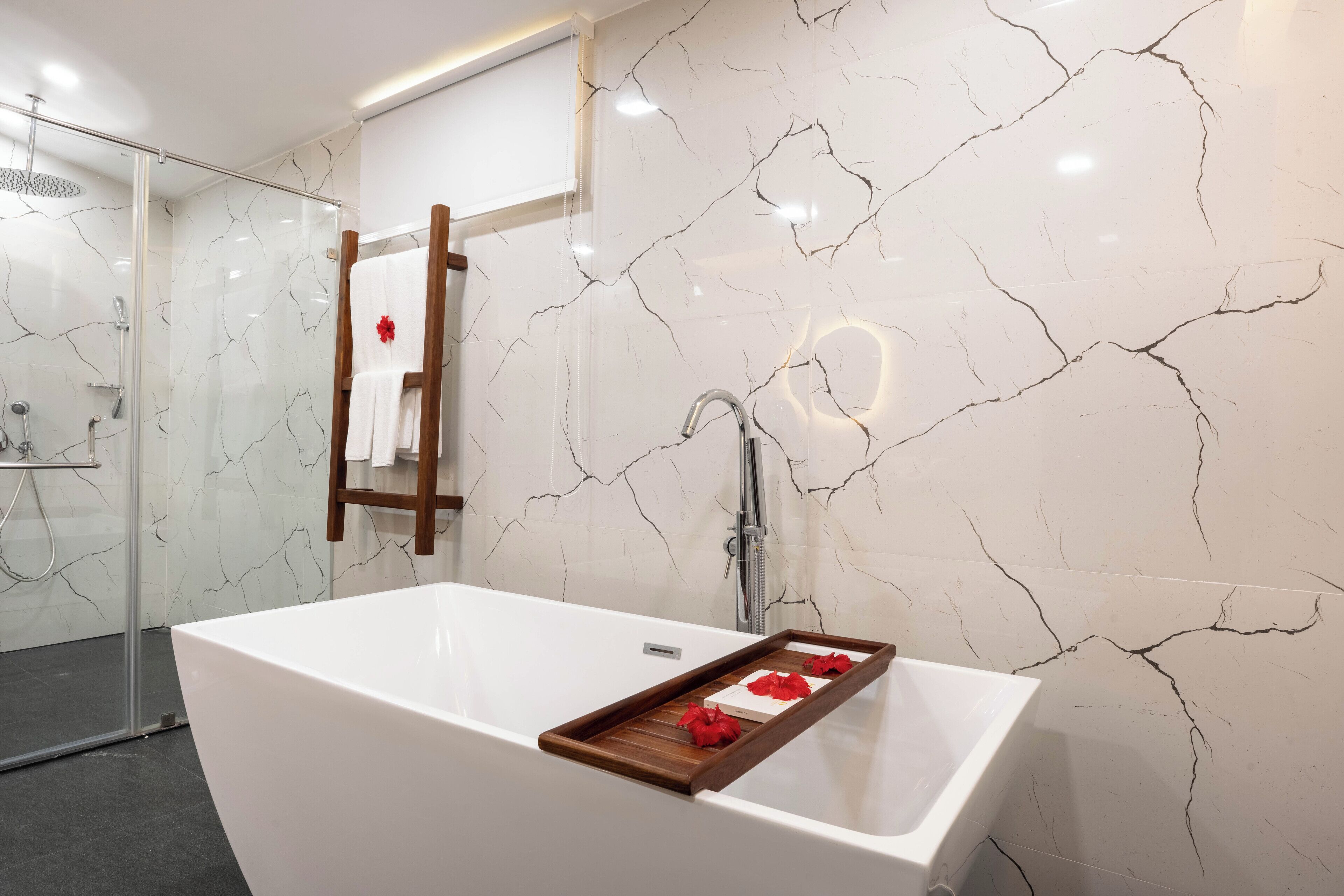 A modern bathroom with a large bathtub, a glass shower enclosure, and a marble wall with a crackled pattern.
