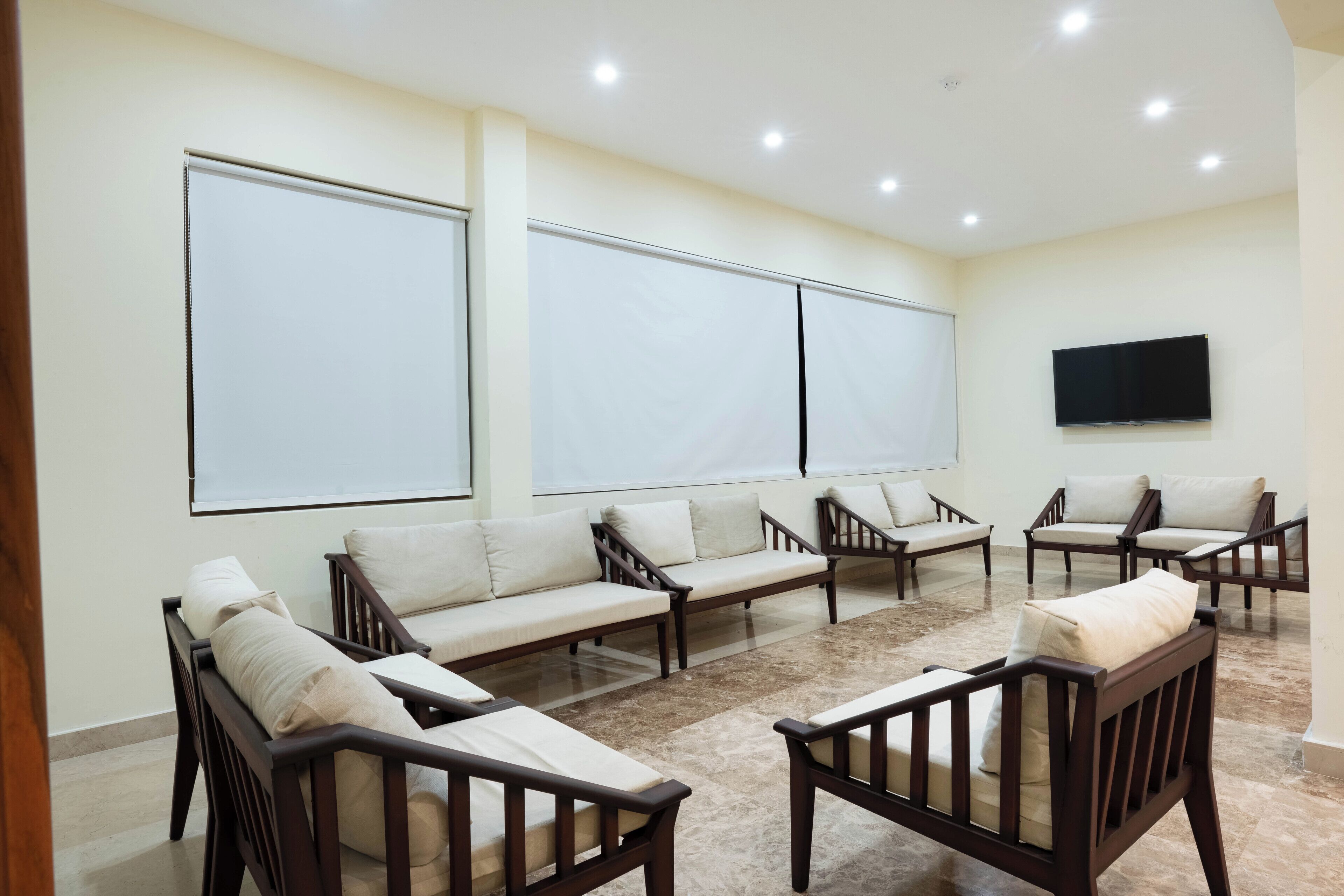A conference room with a large screen, multiple sofas, and chairs arranged for meetings.