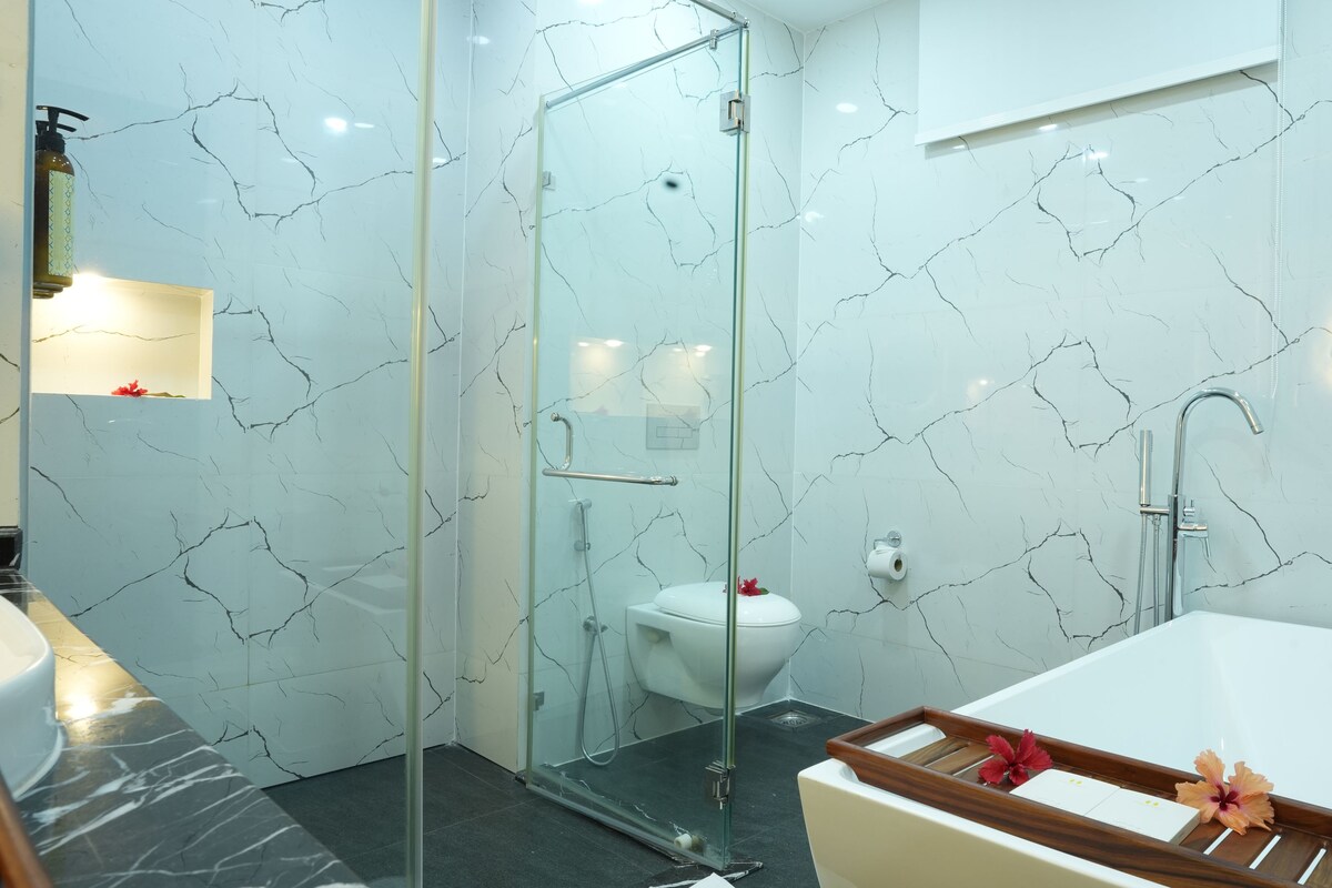 Un baño con ducha de vidrio, inodoro blanco y bañera con detalles de madera.
