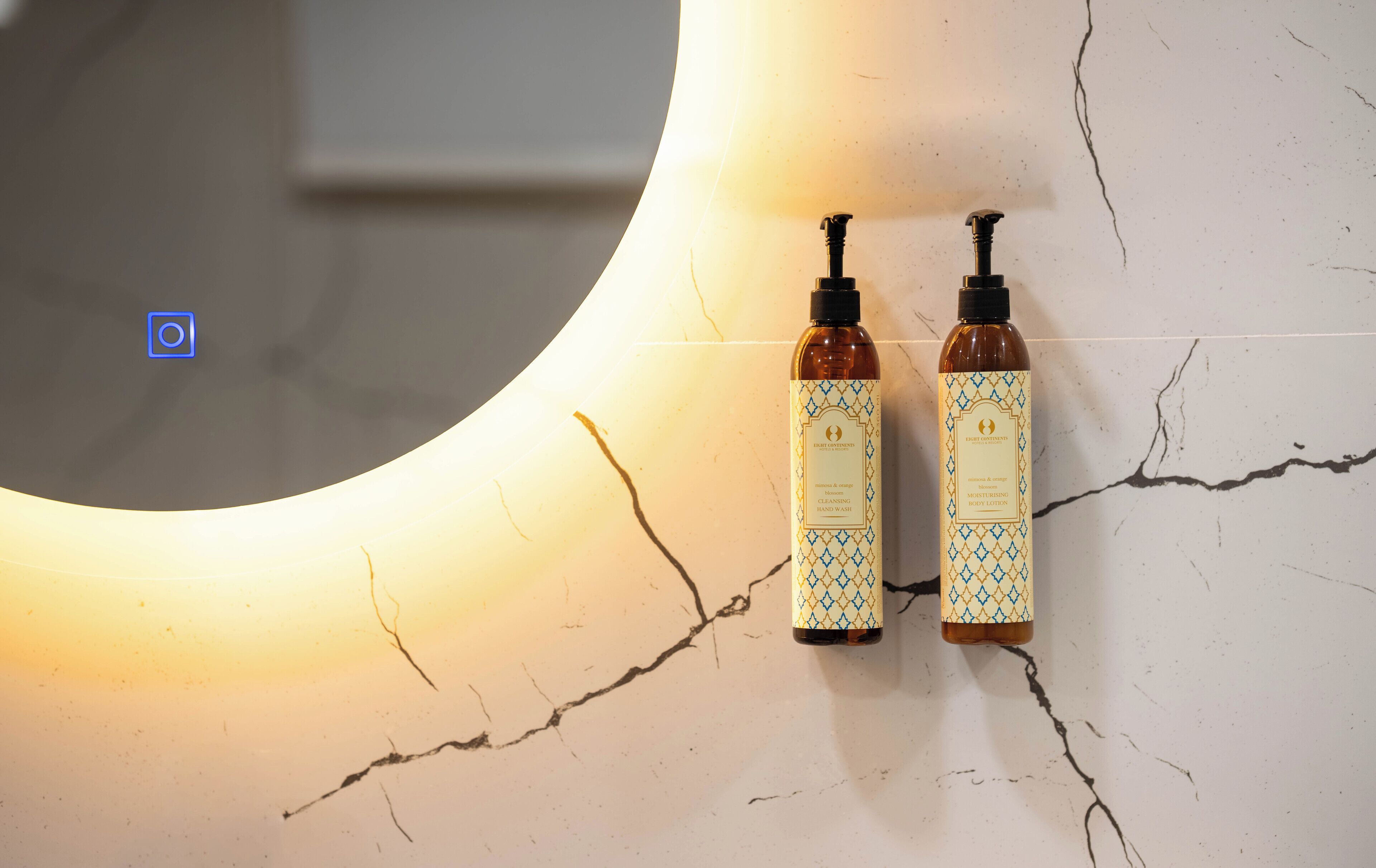 Two bottles of Eight Contients body lotion and hand wash on a cracked white surface.