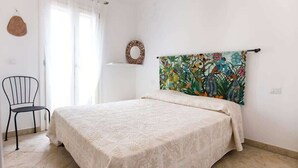 A bedroom with a bed, a chair, a window with curtains, and a wall decoration. - Casa 10 Da Georgette - Affitti Brevi Italia (Valledoria)
