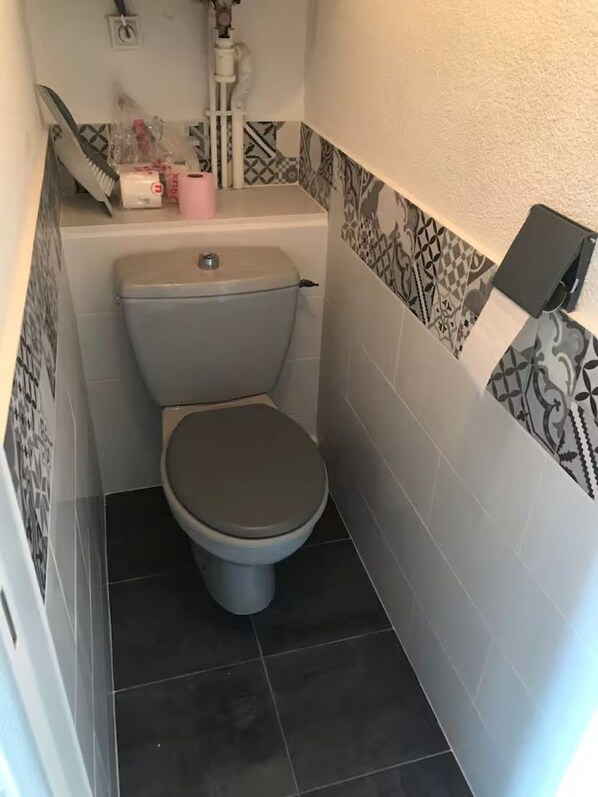 Une petite salle de bain avec des toilettes, un lavabo et un miroir.