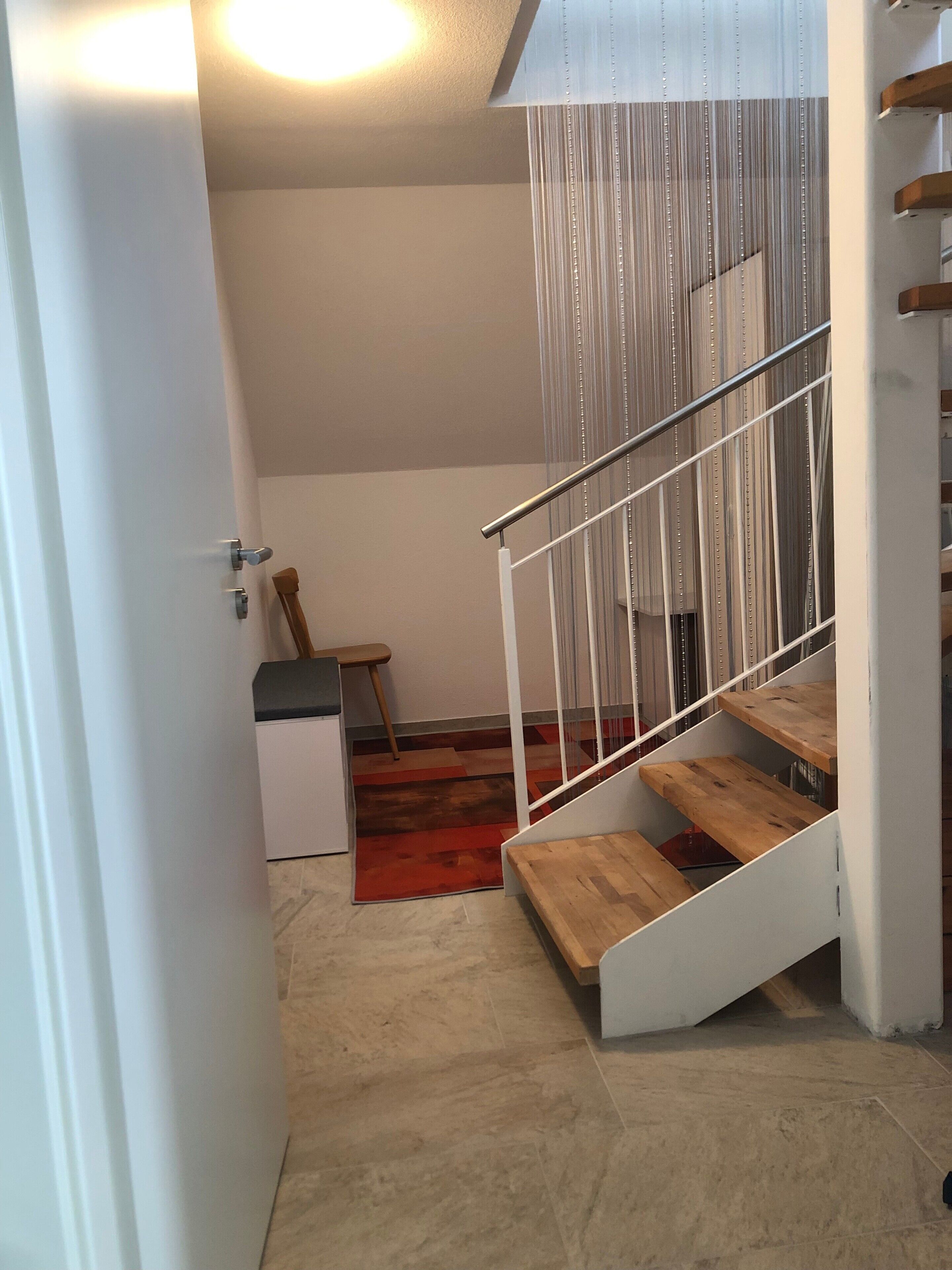 A staircase with wooden steps and metal railings, leading to a landing with a red carpet.