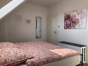 Une chambre à coucher avec un lit, une porte, un miroir et un radiateur.