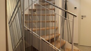 A modern staircase with metal railings and wooden steps, leading to an upper floor. - Aurora Lodge (92 m²) with Balcony and Wi-Fi (Engstingen)