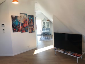 Un intérieur moderne comprenant un coin repas, un téléviseur à écran plat et des œuvres d’art accrochées aux murs.