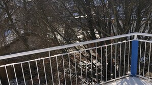 A snow-covered balcony with a white metal railing and a blue post. - Aurora Lodge (92 m²) with Balcony and Wi-Fi (Engstingen)