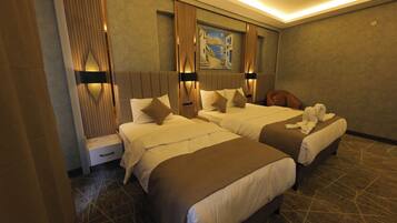 A hotel room with two beds, a nightstand, a wall-mounted artwork, and a patterned carpet.