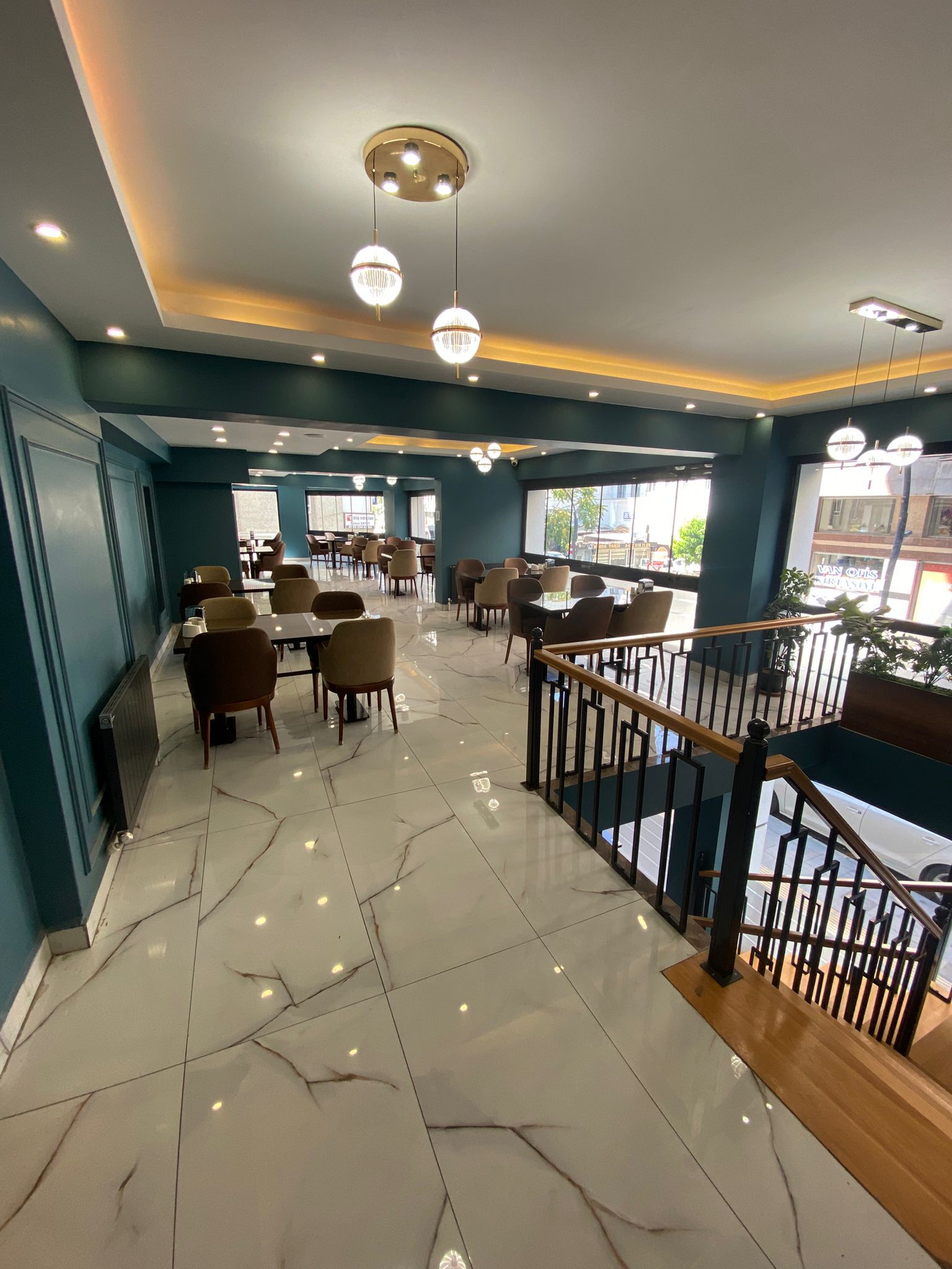 Un interior de restaurante con suelo de mármol, varias mesas de comedor, sillas e iluminación colgante.