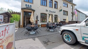 A building with a sign reading 'B&B St. Wendel' and outdoor seating with umbrellas.