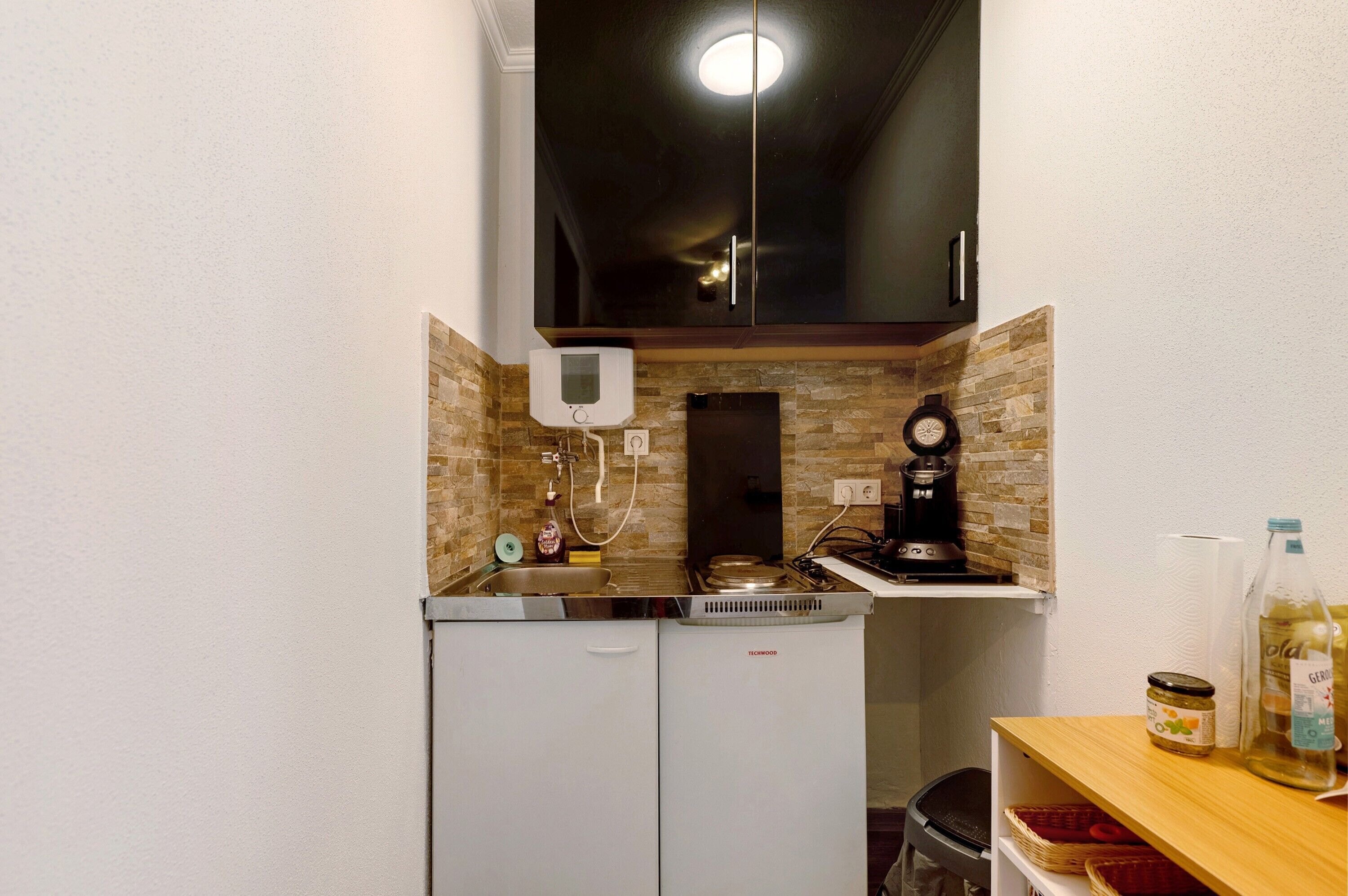 A compact kitchen with a refrigerator, stove, sink, and a small countertop.