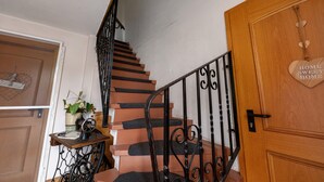 A staircase with black iron railings, a wooden door with a heart-shaped decoration, and a small table with a vase and a clock. - Apartment '7' with Air Conditioning, Shared Garden and Wi-Fi (Thaleischweiler-Fröschen)