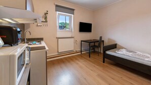 A compact room with a kitchenette, a window with a view, a flat-screen TV, a sofa, and a small table. - Apartment '7' with Air Conditioning, Shared Garden and Wi-Fi (Thaleischweiler-Fröschen)