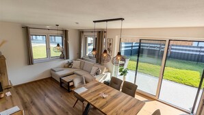 Een moderne woonkamer met houten vloer, een grote eettafel en een zithoek.