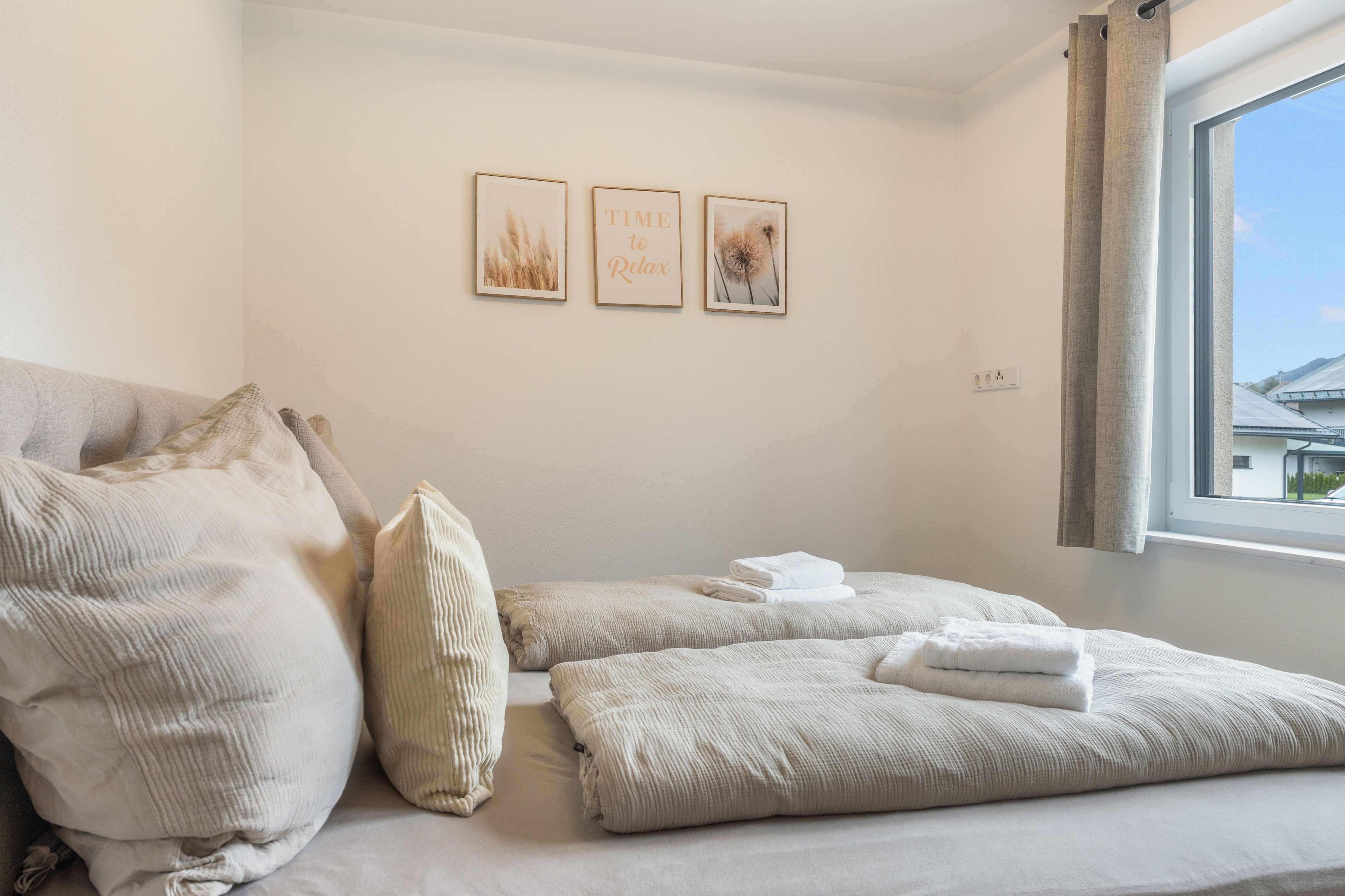 Ein Hotelzimmer mit Bett, Kissen, einem Fenster und Wandbildern.