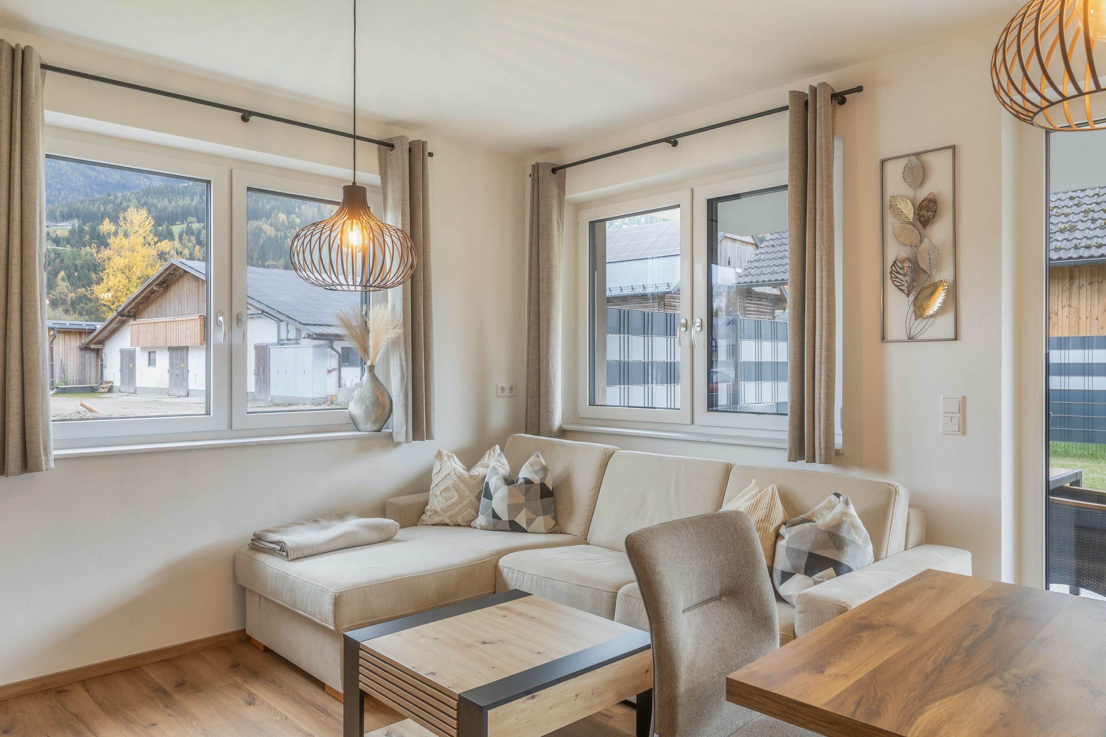 Un salon moderne avec un canapé, une table à manger en bois et un luminaire suspendu.